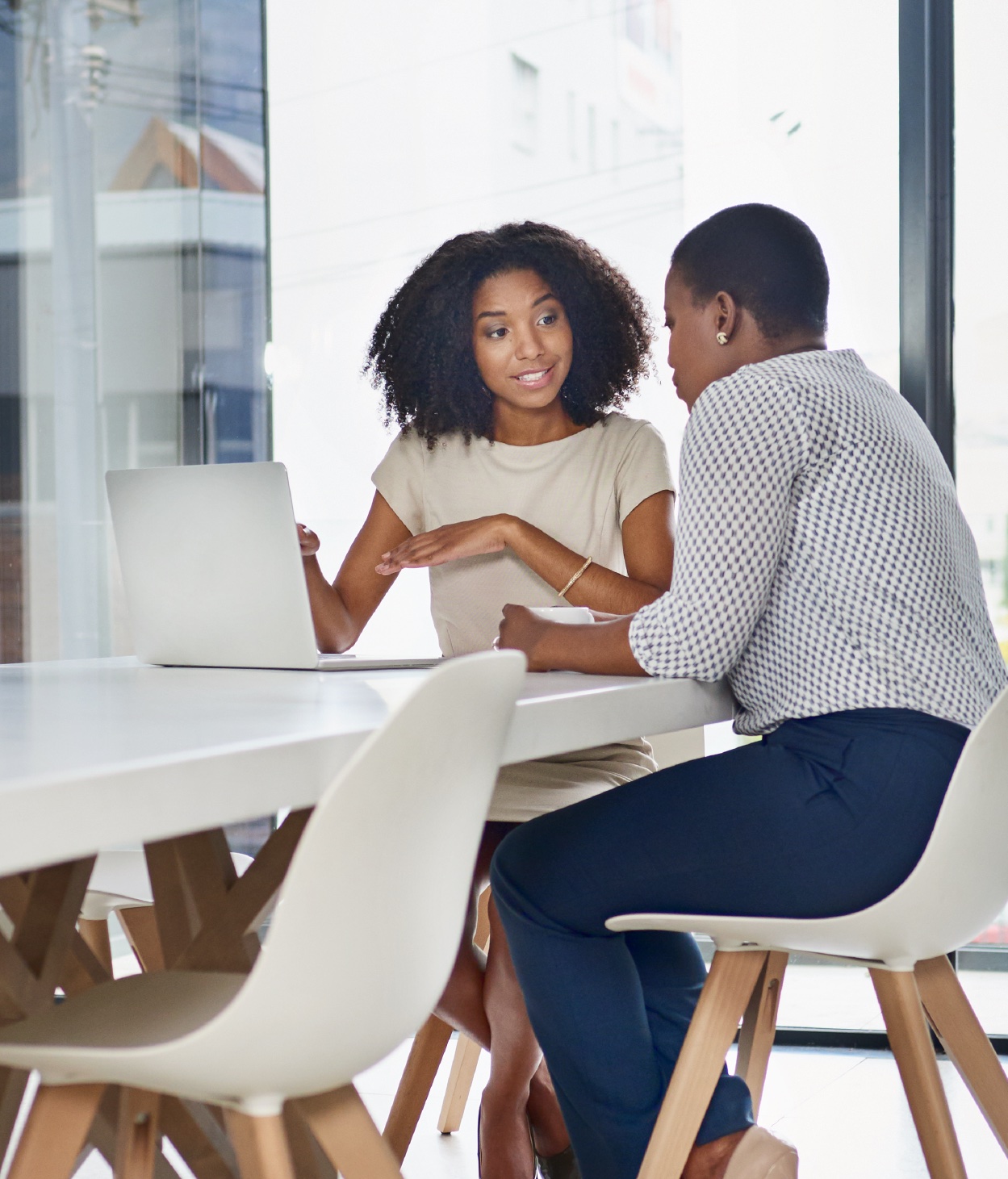 Two Black businesswomen collaborate on a project with a laptop.